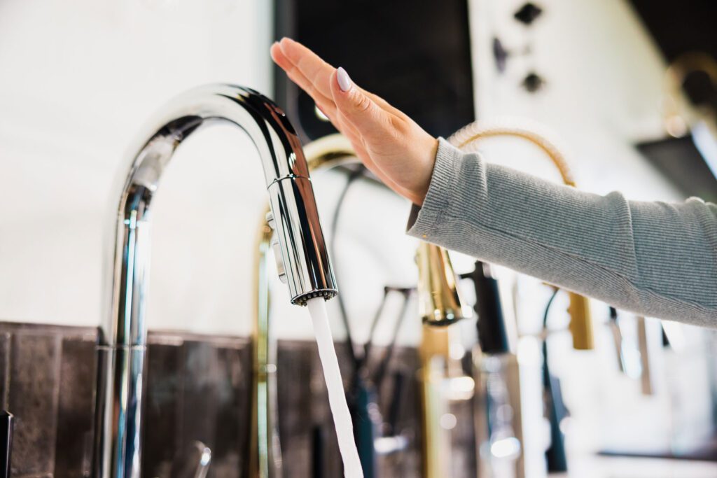 Hand activating kitchen sink faucet in Longley showroom